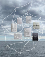 Load image into Gallery viewer, New Alchemy Drafts poetry zines arranged over a sea and cloudy sky, with white geometric linework.
